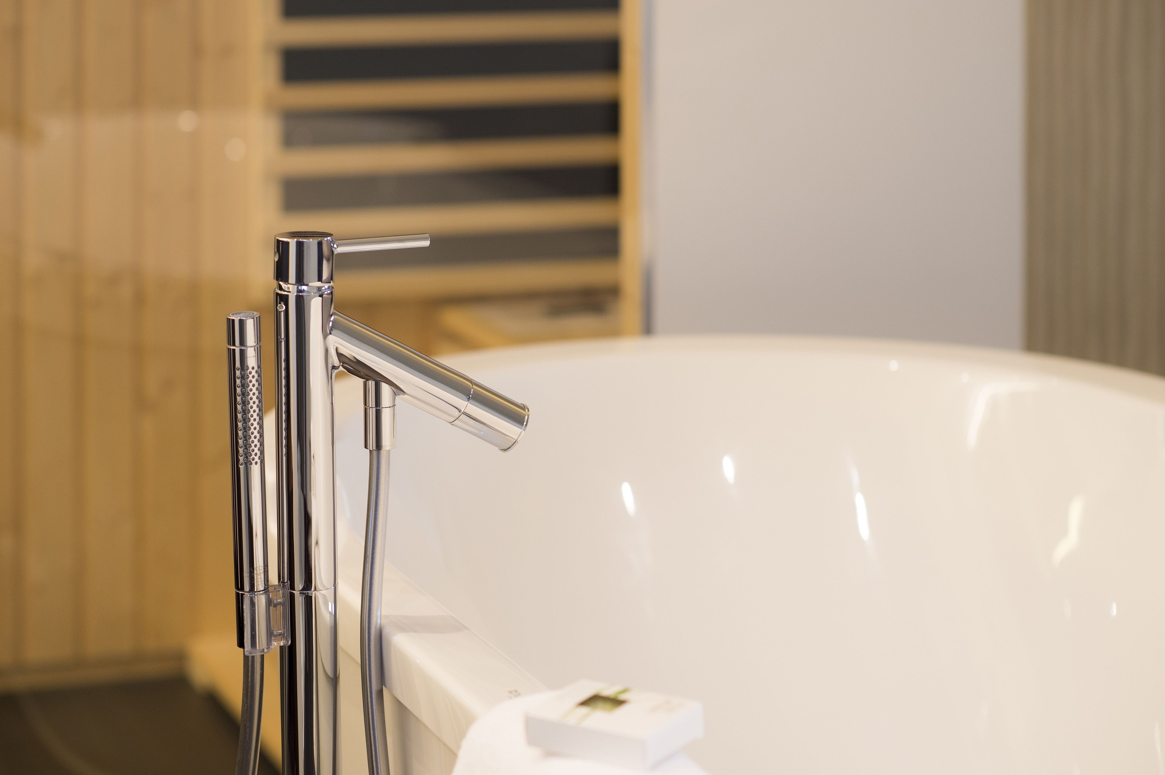 A modern bathroom with a chrome faucet and a white bathtub.