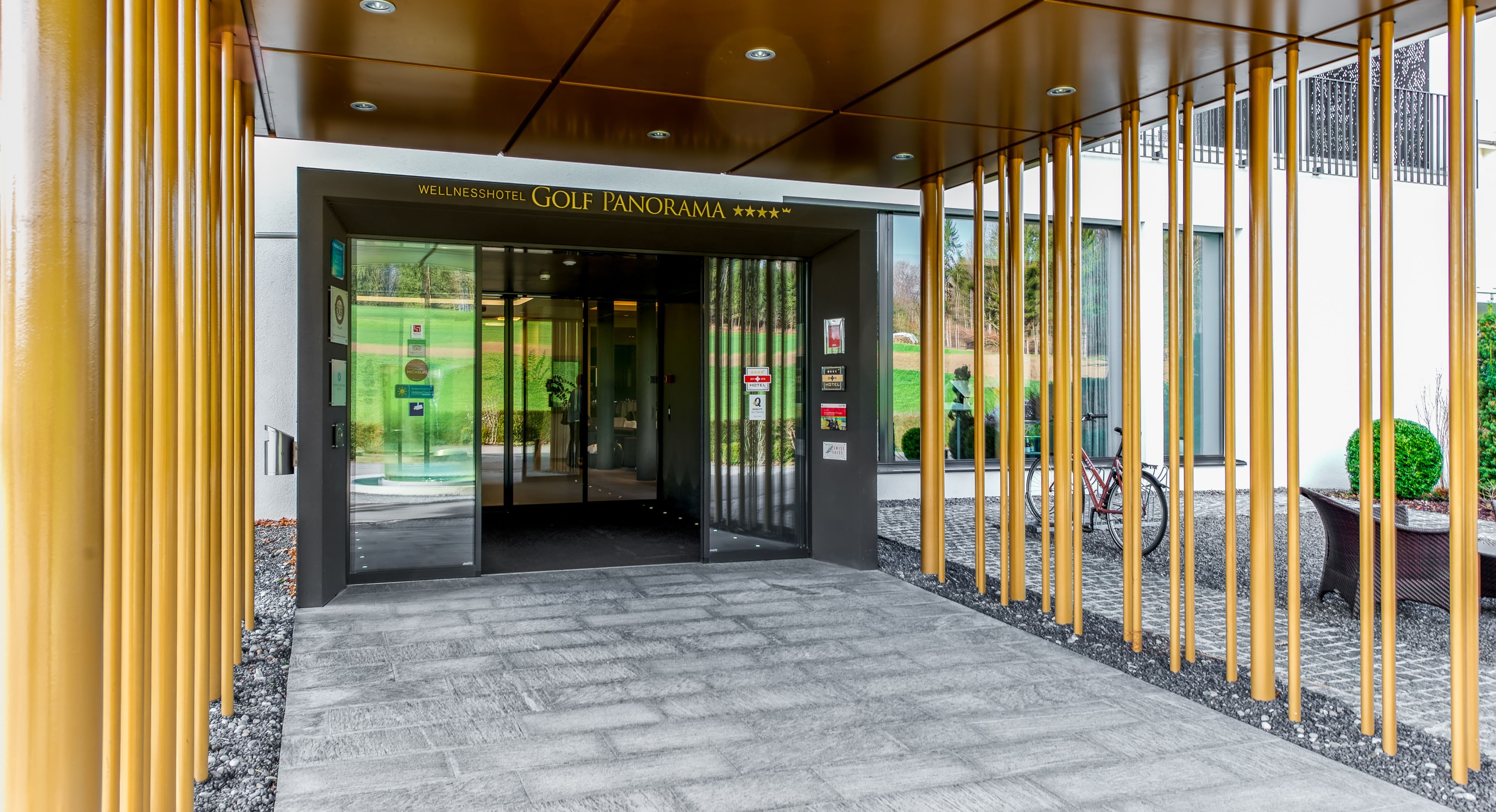 Entrada moderna de un hotel con un cartel que dice "WellnessHotel Golf Panorama".