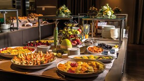 A buffet with various fruits and vegetables, including apples, bananas, and oranges, arranged on a table with multiple serving dishes.