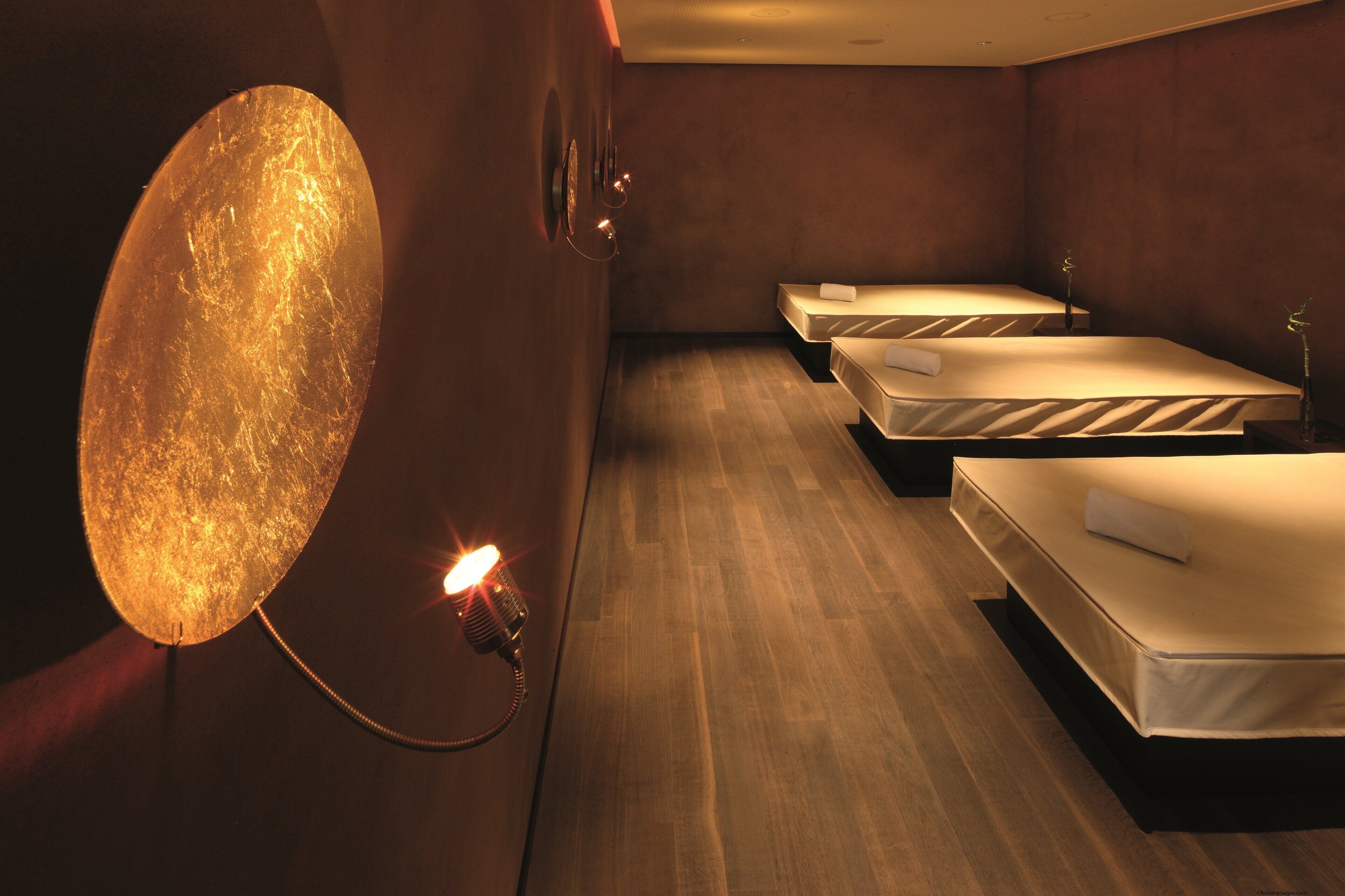 A hotel room with a large wall-mounted light fixture, two beds, and a wooden floor.