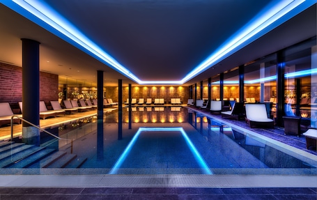 Una piscina techada, sillones reclinables de piscina. Small Luxury Hotel Wellnesshotel Golfpanorama