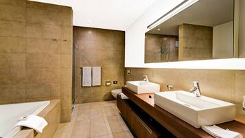 A modern bathroom with a bathtub, two sinks, and a large mirror.