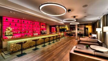 A modern bar area with a red-lit wine rack, a bar counter, and seating.