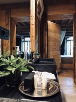 A wooden interior with a reception desk, potted plants, and a tray with toiletries.