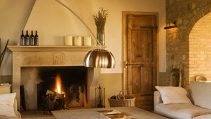 Una sala de estar acogedora con chimenea, vigas de madera, paredes de piedra y un sofá de cuero.