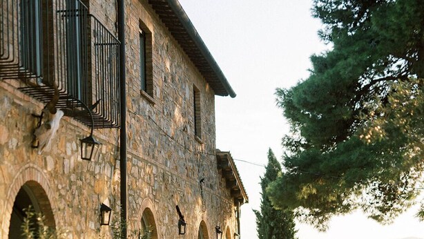 Un edificio de piedra con ventanas arqueadas y terraza.