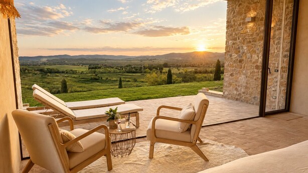 A balcony with a view of a green landscape and a sunset. There are two lounge chairs and a small table with a glass of wine. - Conti di San Bonifacio Wine Resort (Gavorrano)