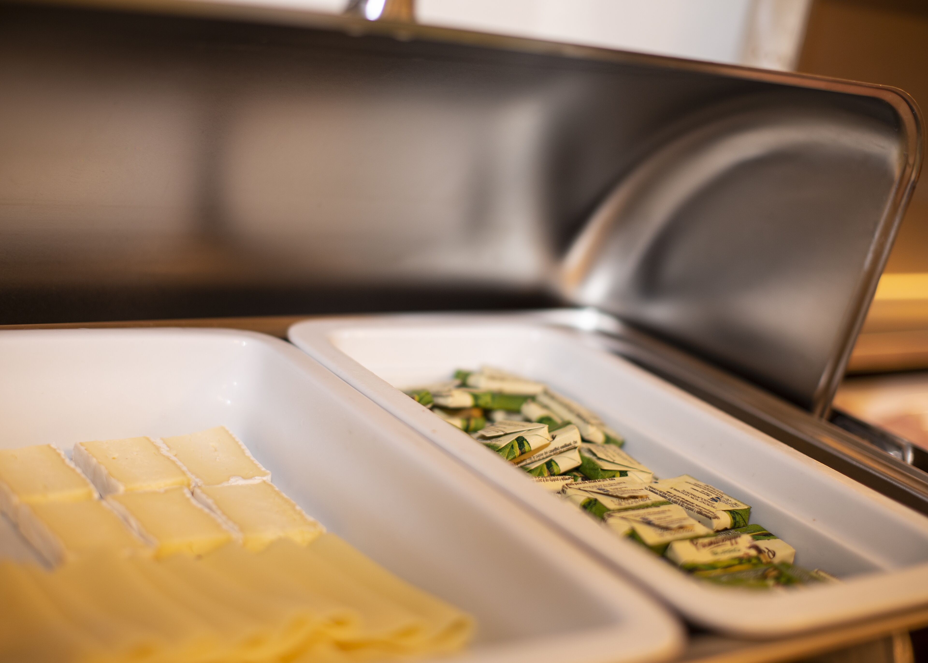 A buffet setup with trays of butter and packaged food items.