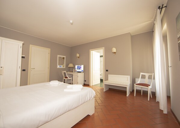 A hotel room with a large bed, a desk with a computer, a chair, and a small table. - HC Hotel Il Gelso Pontevico (Pontevico)