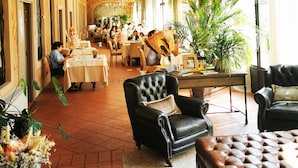 A spacious hotel lobby with a long corridor, multiple dining areas, and a chandelier. - HC Hotel Il Gelso Pontevico (Pontevico)