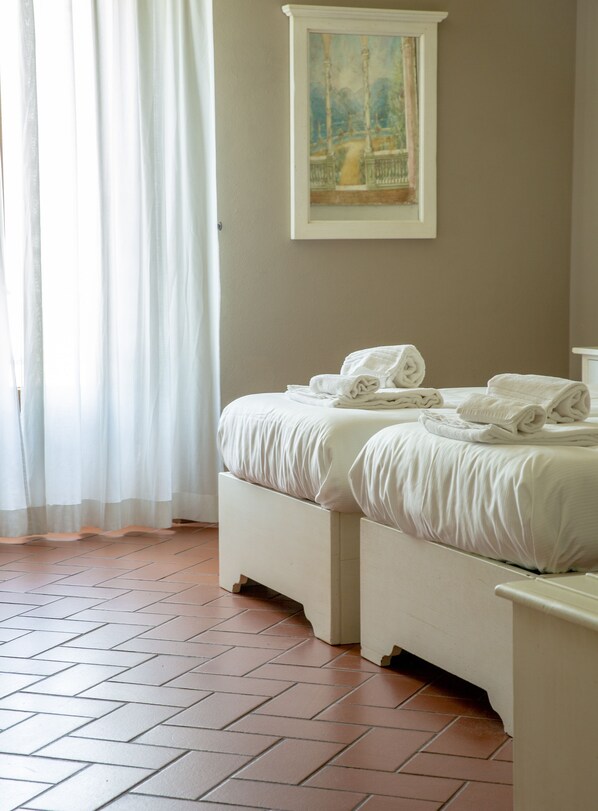 Un dormitorio con dos camas, un cuadro en la pared y una ventana con cortinas.