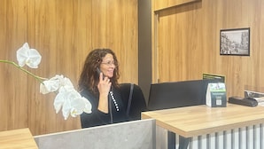 Un área de recepción con paneles de madera, un mostrador de recepción, una computadora y una imagen en un marco en la pared.