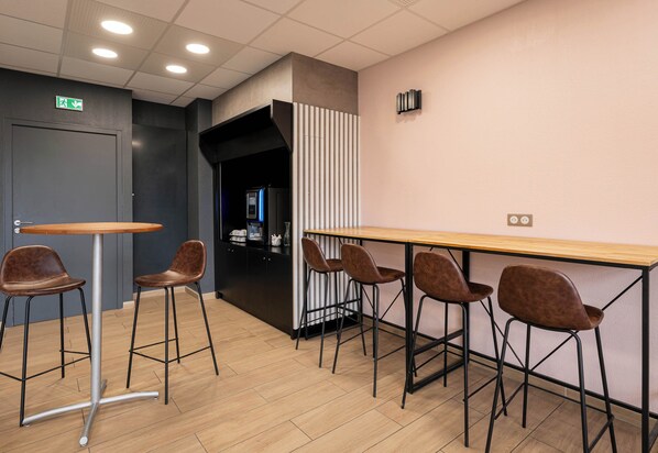Un área de bar moderna con una mesa de madera y cuatro taburetes, un separador negro y una señal de salida visible.