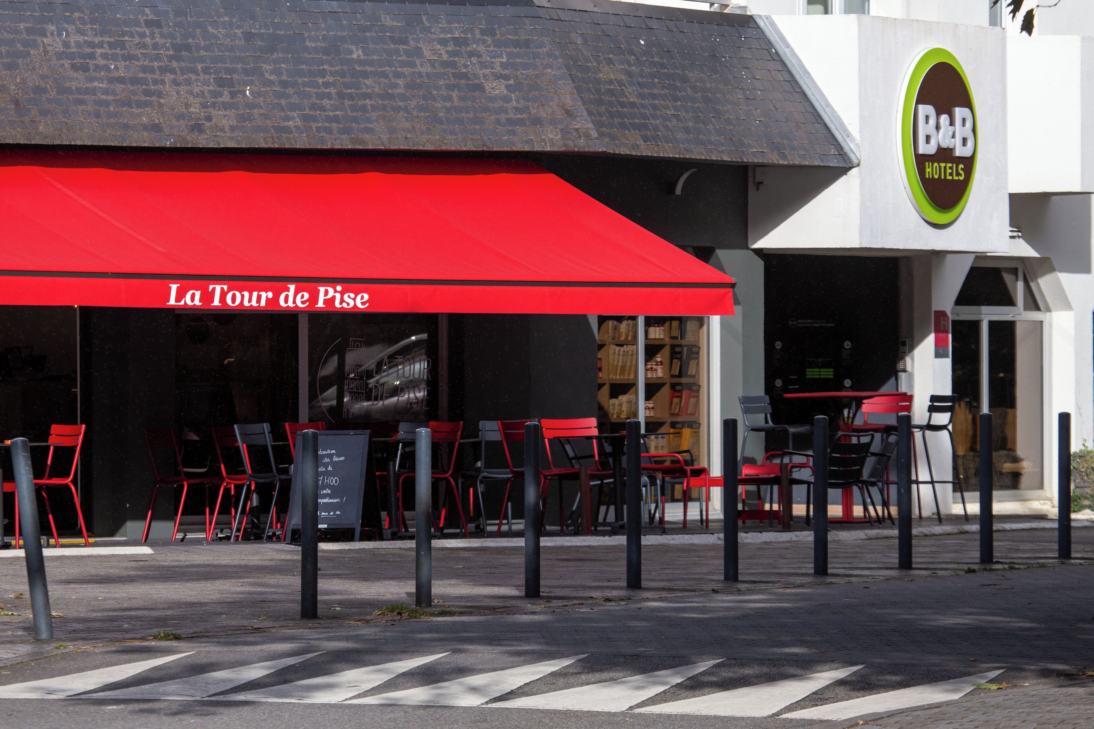 A B&B hotel with a red awning and outdoor seating area.