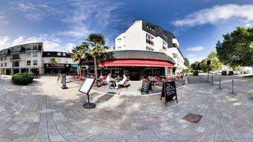 A café with outdoor seating, a red awning, and a signboard.