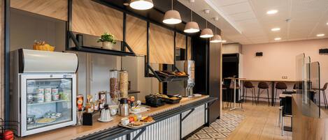 A modern breakfast bar with a refrigerator, coffee machine, and various food items.