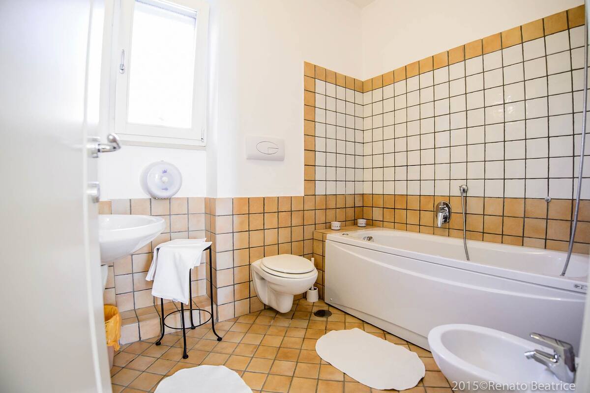 Et badeværelse med håndvask, toilet, badekar og bidét.