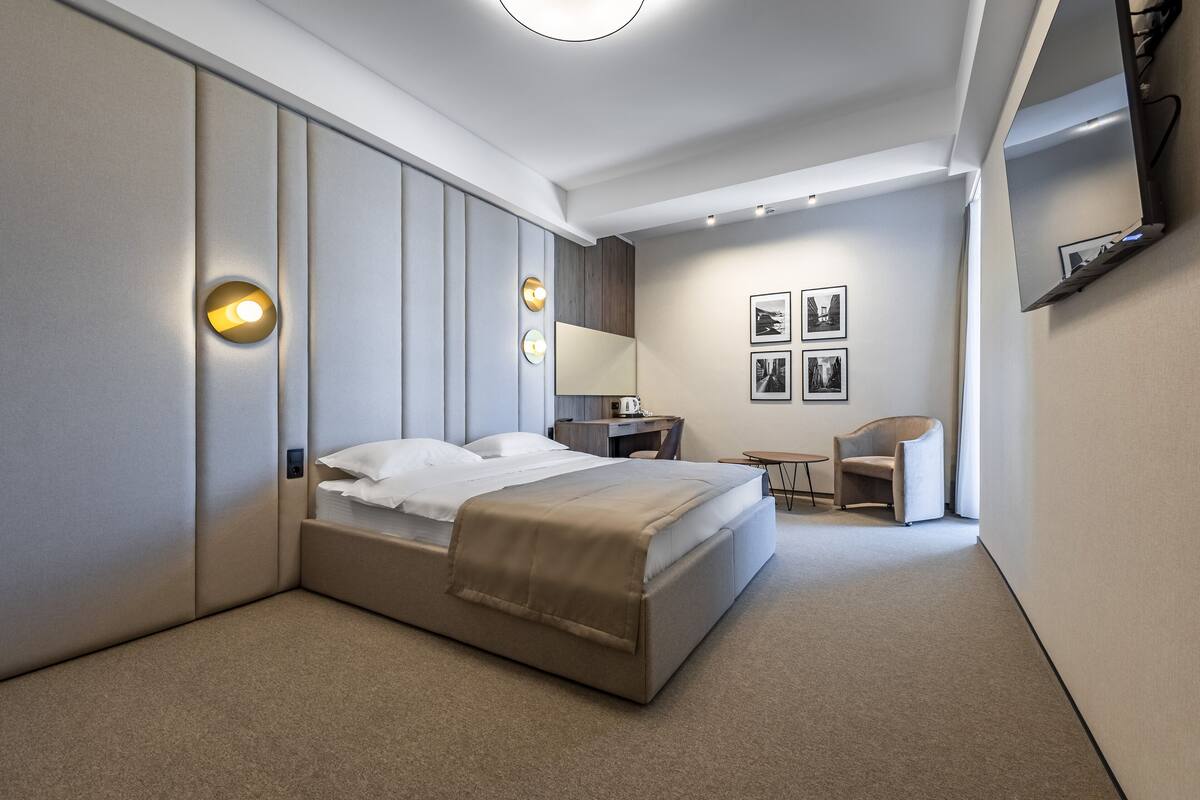 A modern hotel room with a large bed, bedside tables, a desk, and a chair.