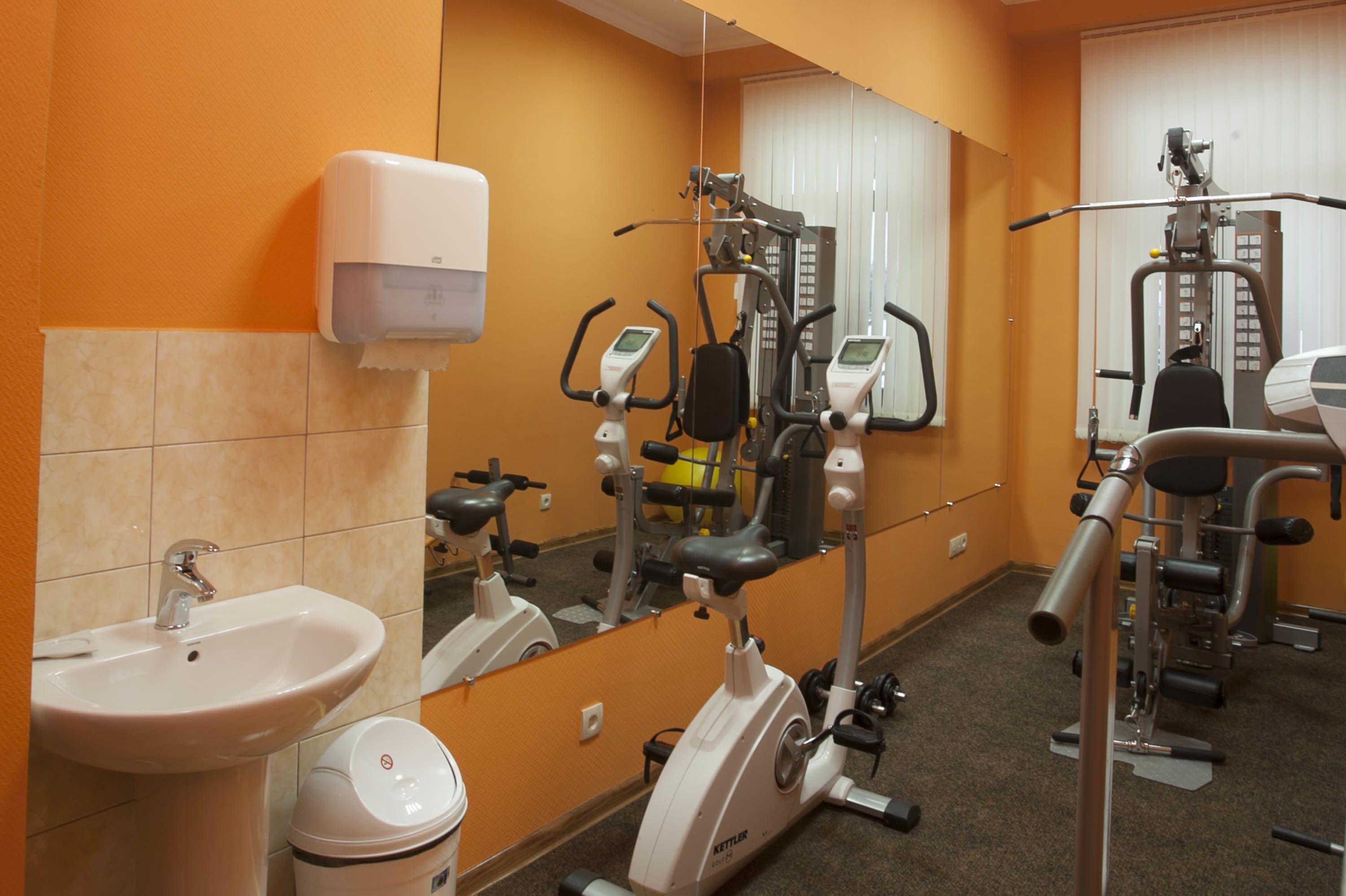 A gym with exercise equipment, a sink, and a mirror.