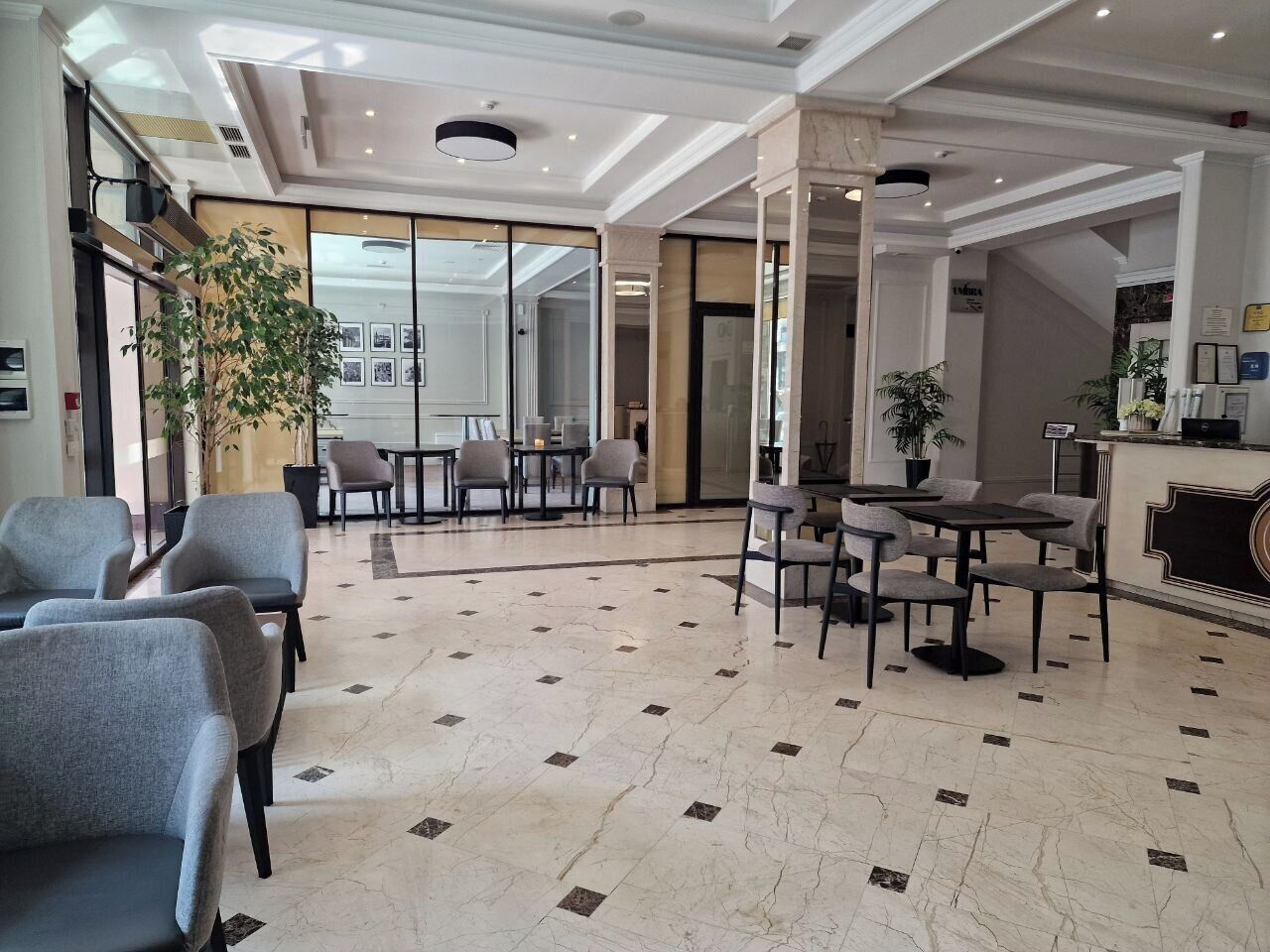 Un vestíbulo de hotel con zonas de estar, un mostrador de recepción y un amplio ventanal.