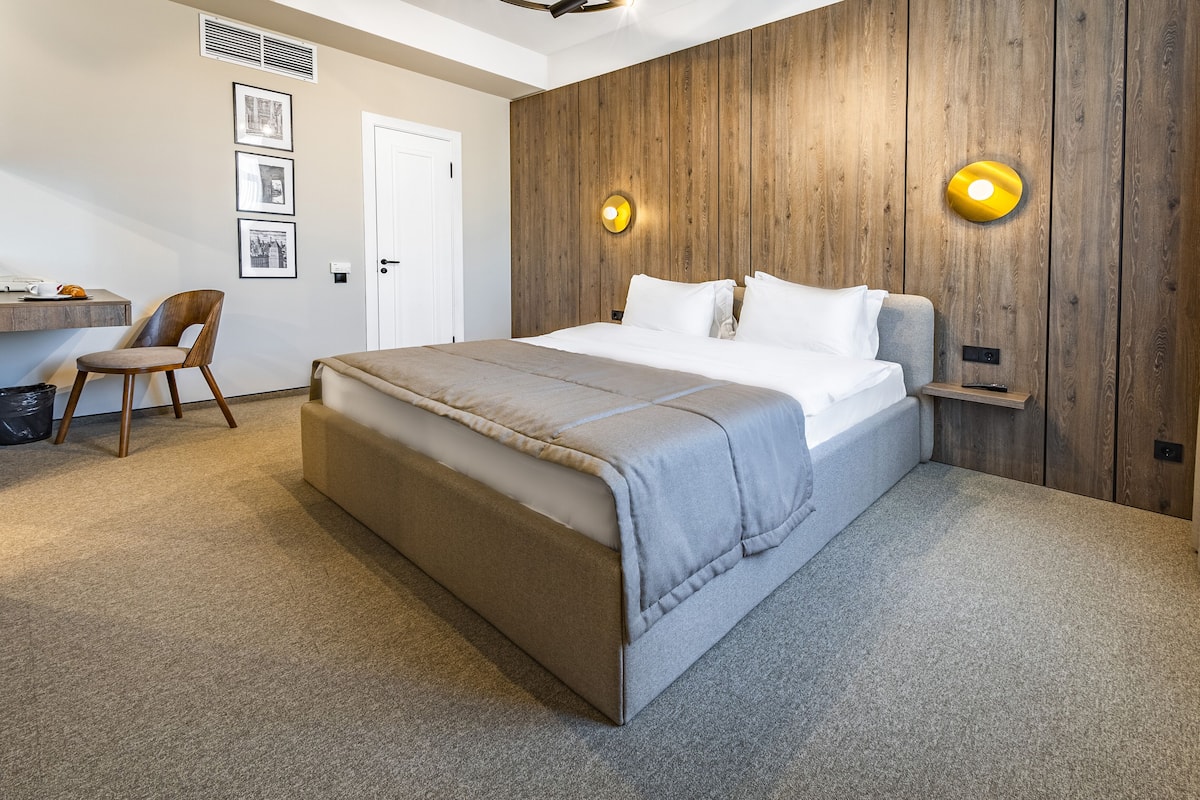 A bedroom with a large bed, a desk, and a chair.