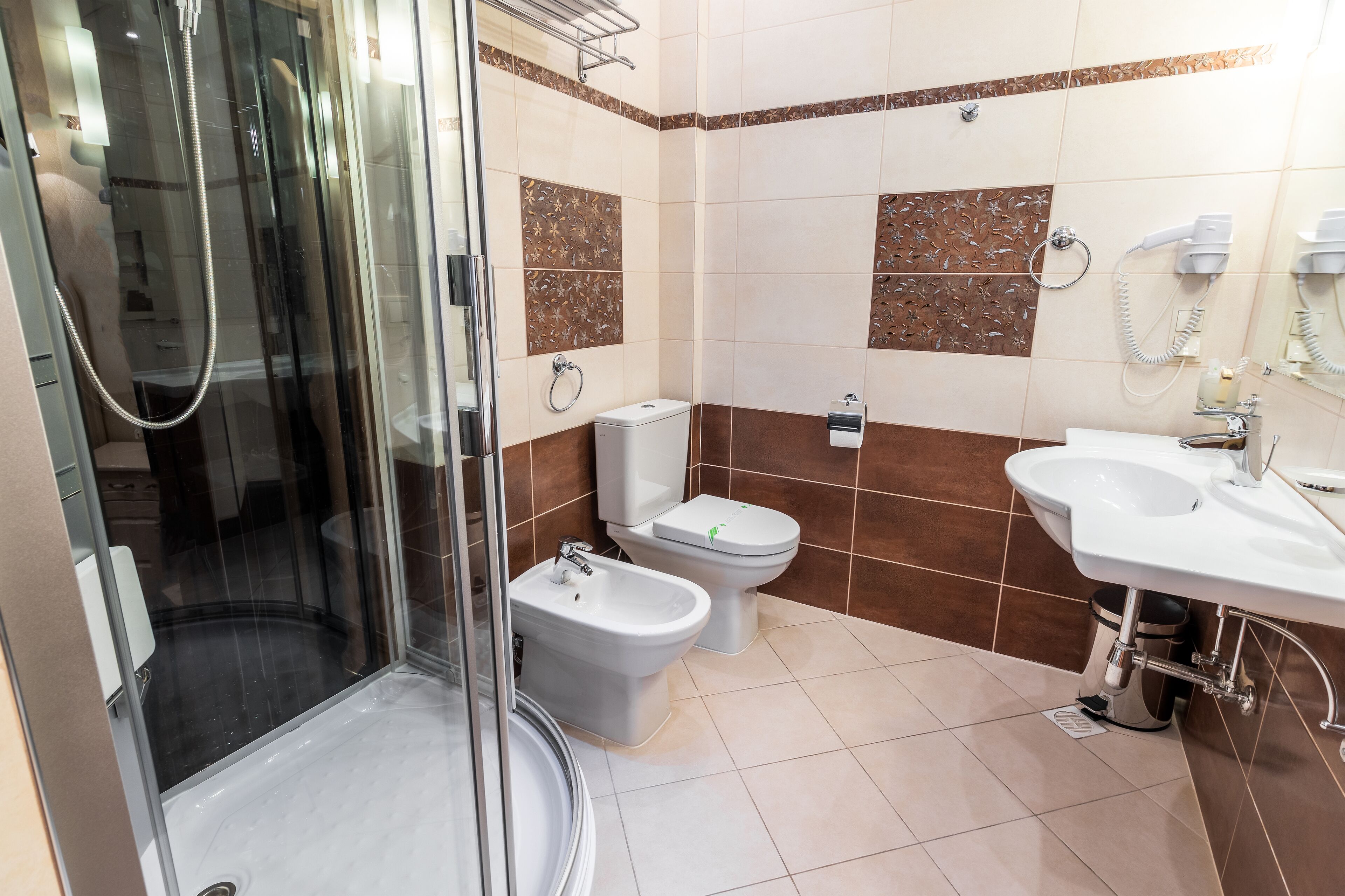 A modern bathroom with a glass-enclosed shower, a bidet, a toilet, and a sink.