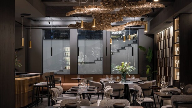 A modern restaurant interior with high ceilings, pendant lighting, and a central seating area with round tables and chairs. - Regency Hotel (Chisinau)