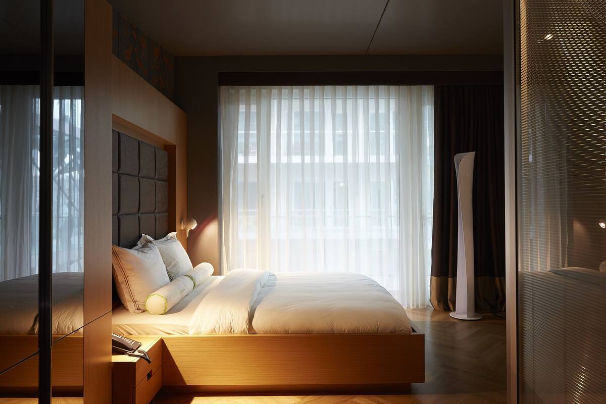 A modern bedroom with a large bed, a bedside table, and a floor lamp.