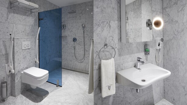Een moderne badkamer met toilet, douche, wastafel en spiegel.