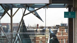 A modern reception area with a glass facade, metal framework, and a sign for Amadi Park Hotel Reception. - Amadi Park Hotel (Amsterdam)