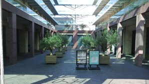 A covered walkway with potted trees and directional signs. - Amadi Park Hotel (Amsterdam)
