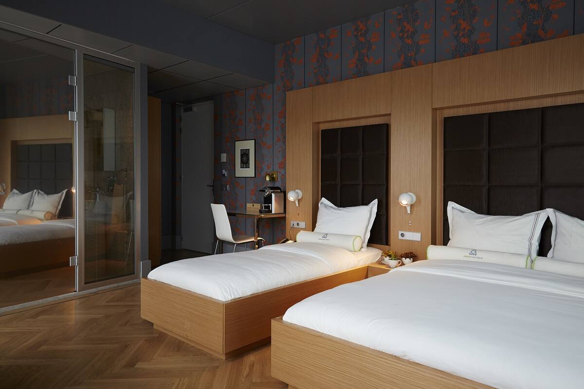 A hotel room with two beds, a desk, and a chair.