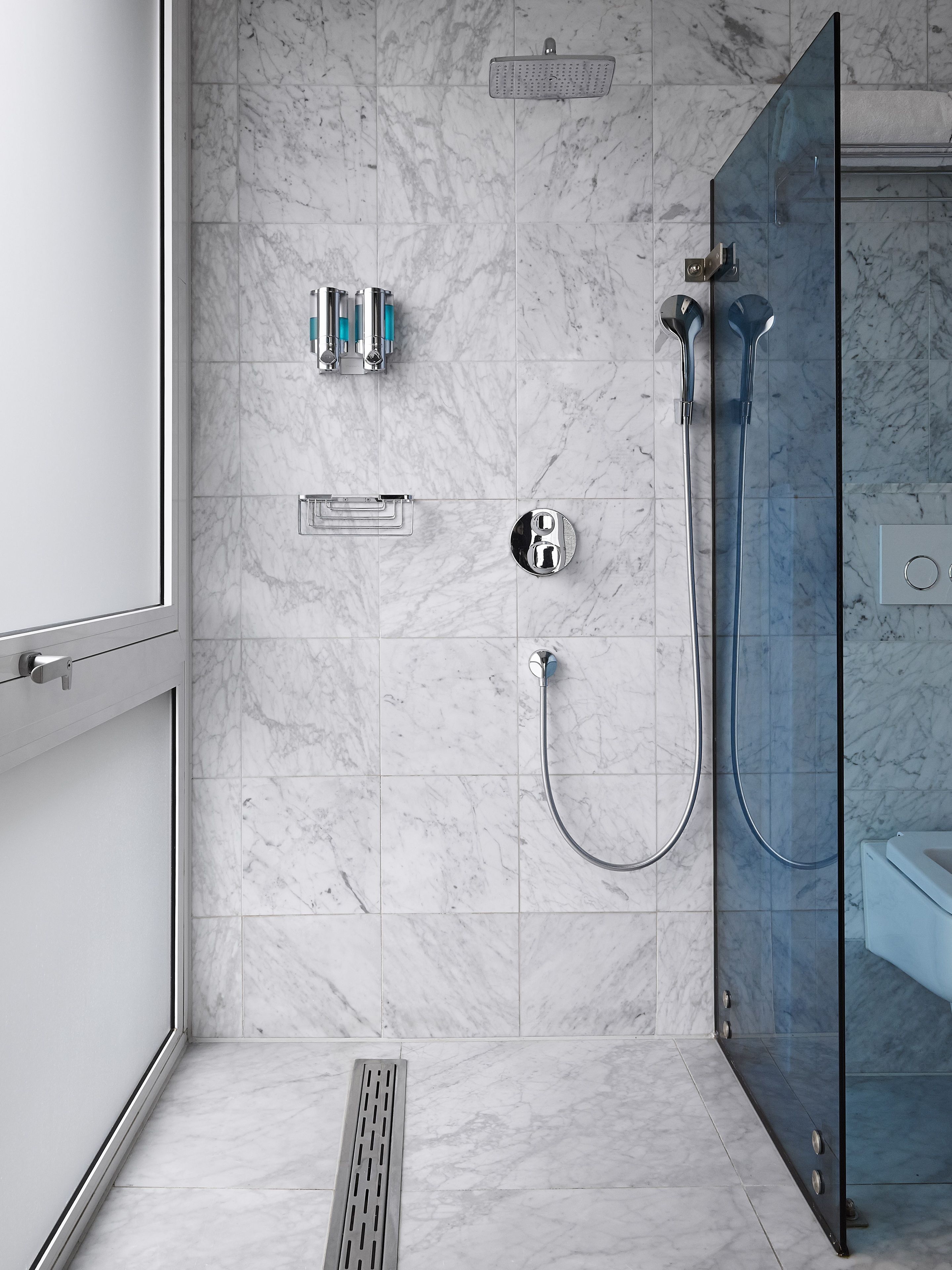A modern bathroom with a glass shower enclosure, a handheld showerhead, and a wall-mounted faucet.