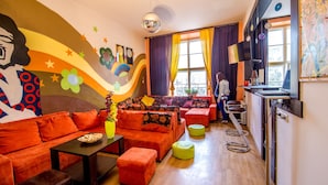Una sala de estar vibrante con sofás naranjas, una mesa de centro y un mural en la pared.