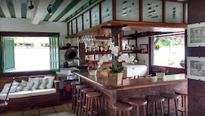 A bar area with stools, a counter, and a refrigerator. - Barla Inn Suites (Búzios)