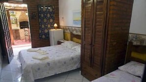 A bedroom with a bed, a wardrobe, and a small table with a lamp. - Pousada Garota de Geriba (BUZIOS)