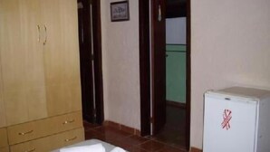 A room with a bed, a wardrobe, a door, and a refrigerator. - Pousada Garota de Geriba (BUZIOS)