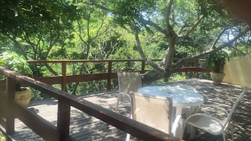 Eine Holzterrasse mit Tisch und Stühlen, umgeben von üppigem Grün.