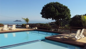 A swimming pool with lounge chairs and a view of the sea.