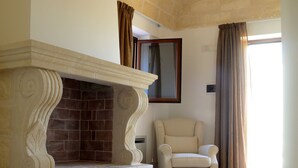 A room with a fireplace, a chair, and a large window with curtains.