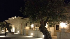 A stone building with arched doorways and a courtyard at night.