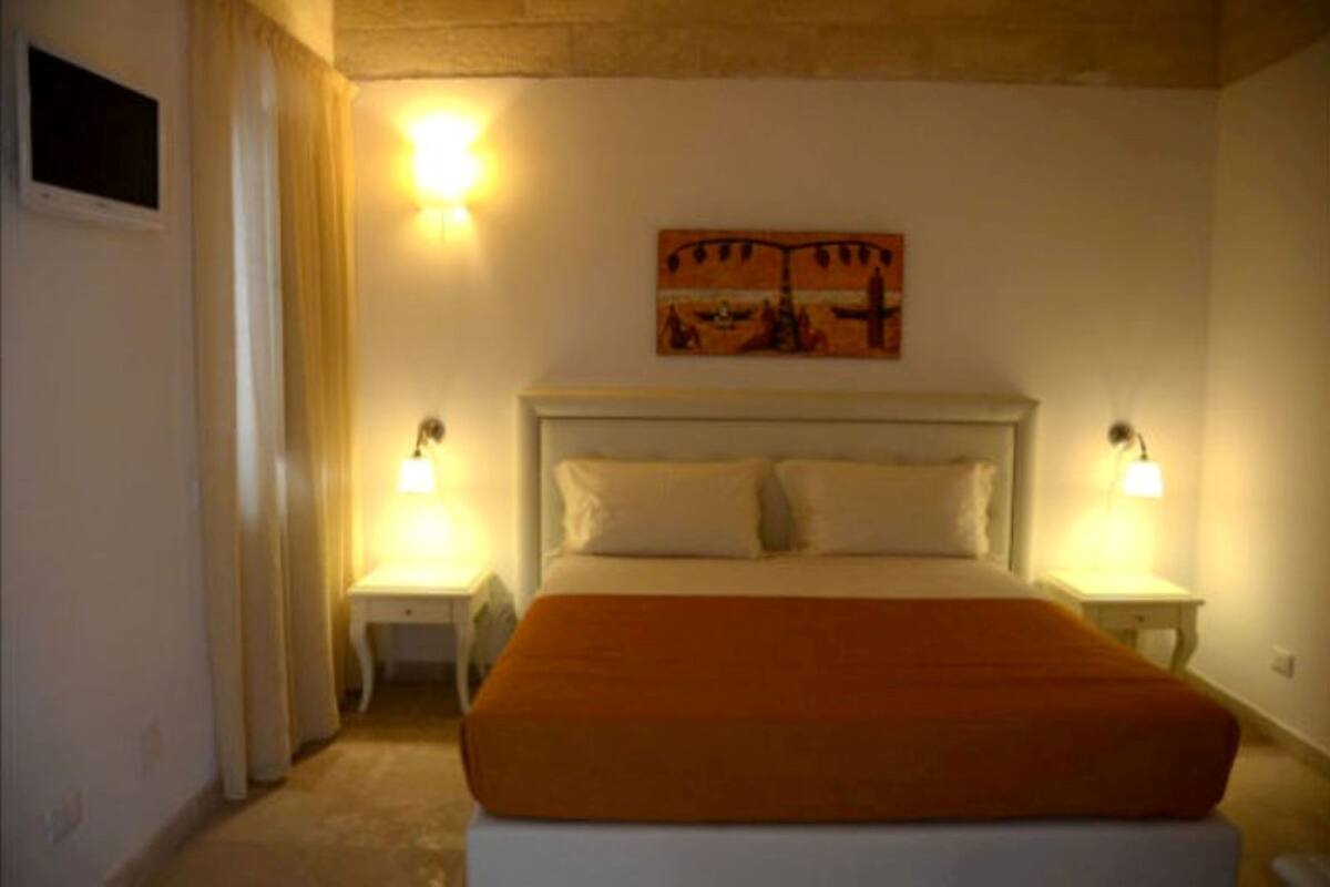 Ein Schlafzimmer mit einem großen Bett, zwei Nachttischen, einem Beistelltisch und einem Bild an der Wand.