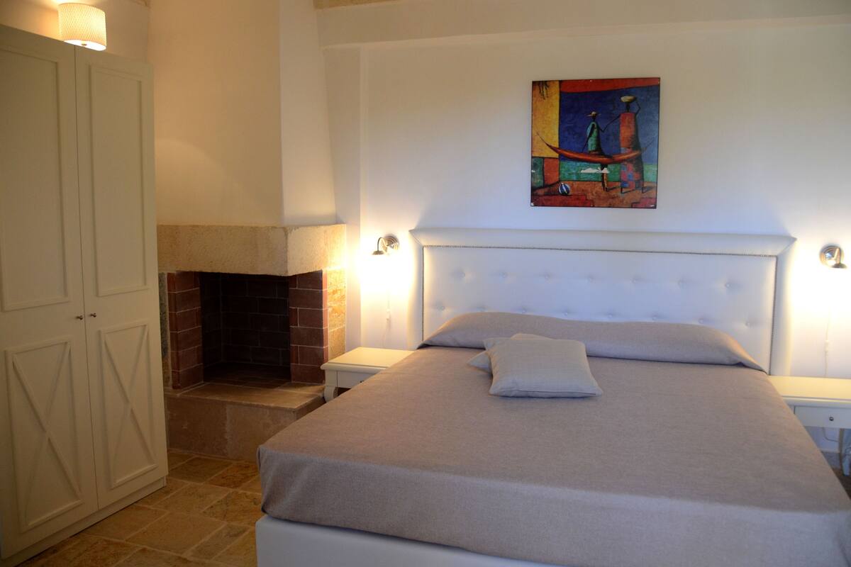 Ein Schlafzimmer mit Bett, Kamin, einem Bild an der Wand und einem Kleiderschrank.