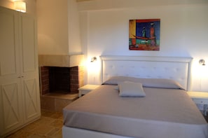 A bedroom with a bed, a fireplace, a painting on the wall, and a wardrobe.