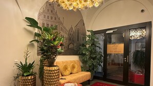 A lobby with a red carpet, a sofa, two large planters, and a decorative ceiling light. - Hotel Schwibbogen Altstadt & Appartements (Görlitz)