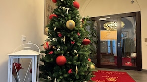 A Christmas tree with ornaments and presents in a hotel lobby. - Hotel Schwibbogen Altstadt & Appartements (Görlitz)