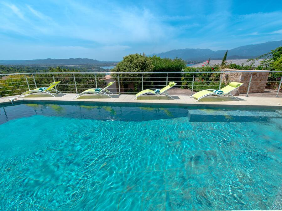 A clear blue pool with lounge chairs and a scenic mountain view.