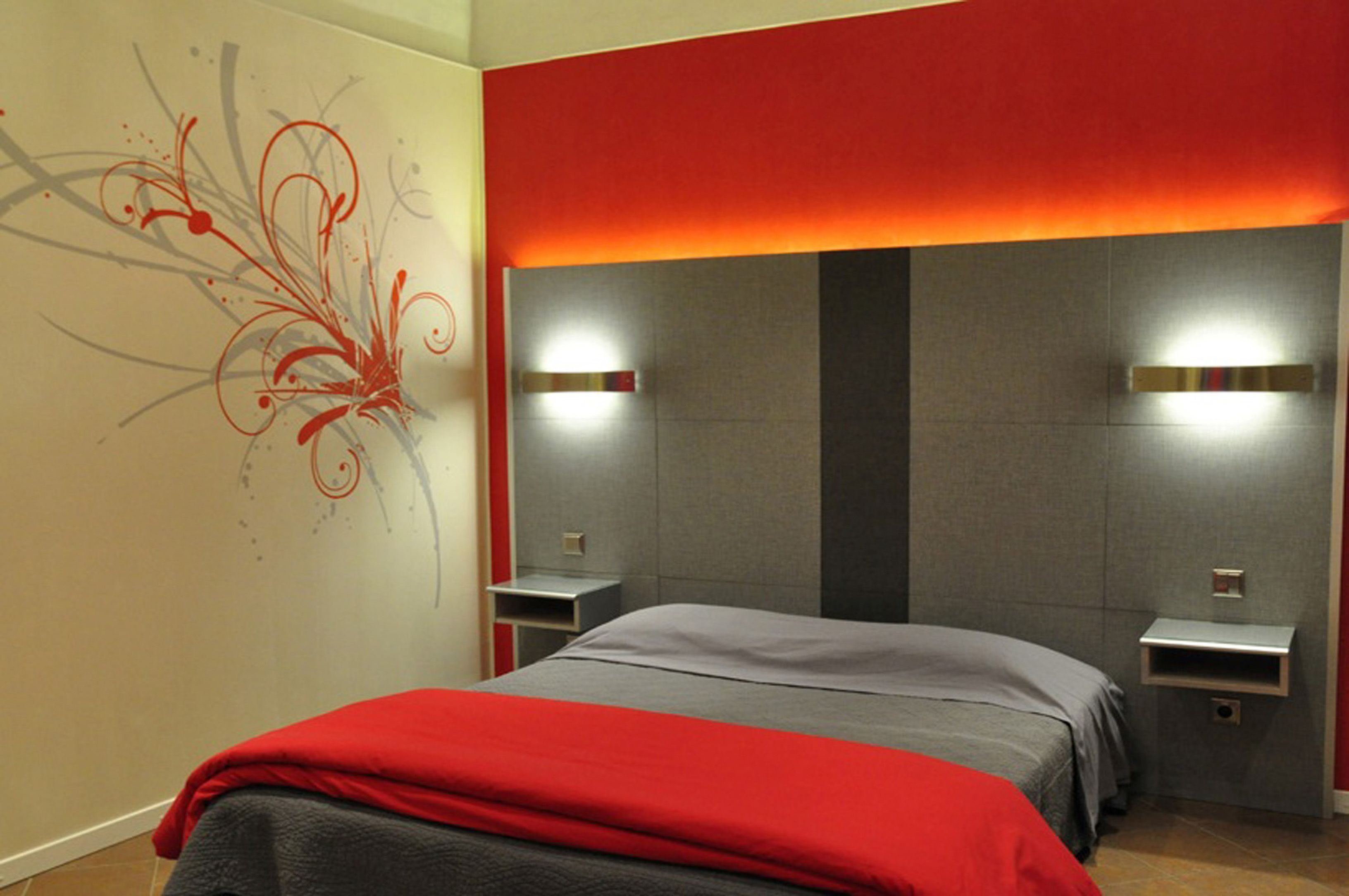 A modern hotel room with a large bed, two bedside tables, and a decorative wall mural.