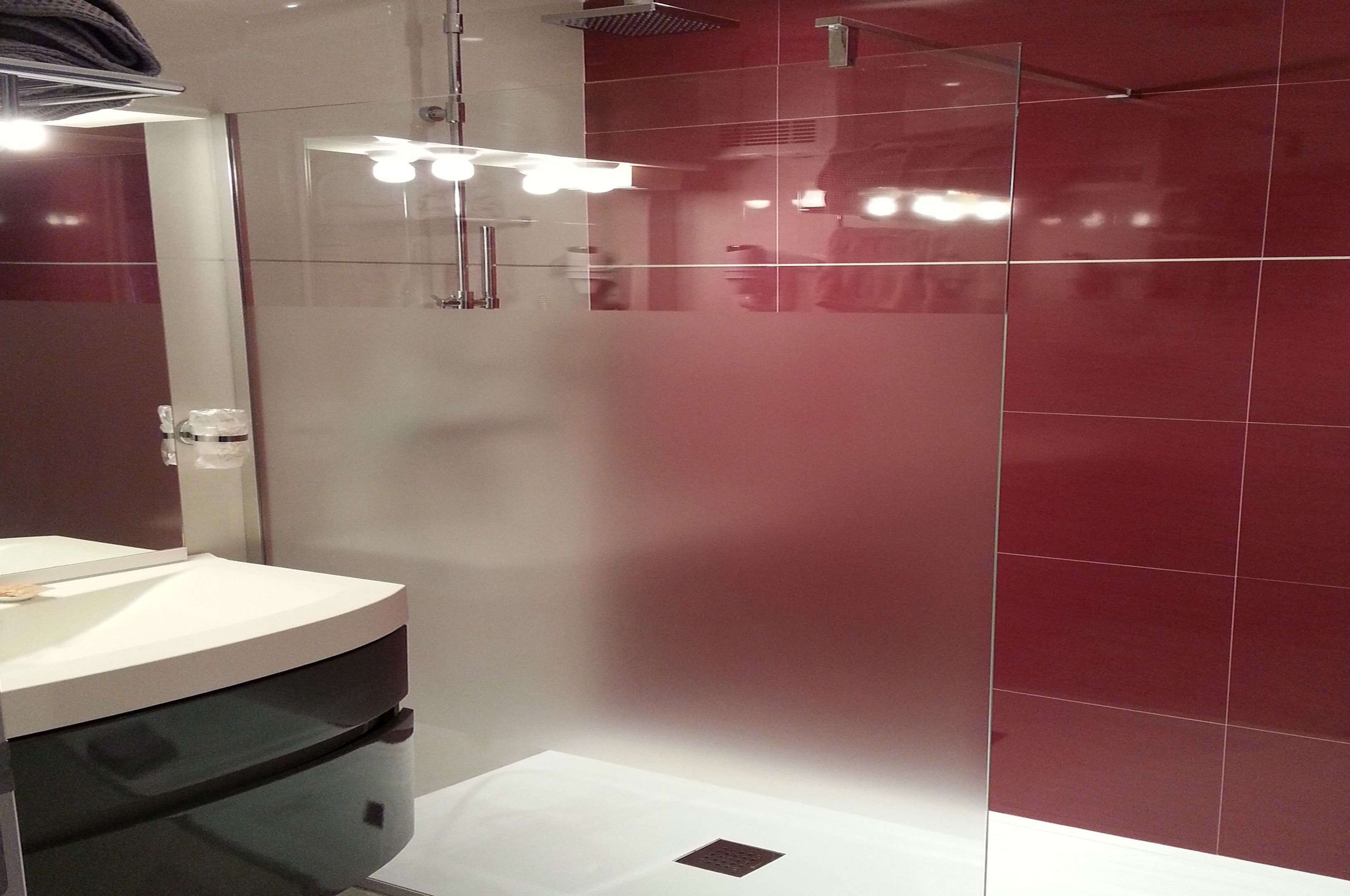 Un baño moderno con ducha de vidrio, un lavamanos blanco y un espejo.