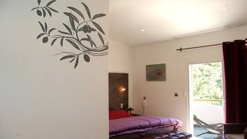 A bedroom with a bed, a bench, a wall decoration, a painting, and a view of the outdoors.